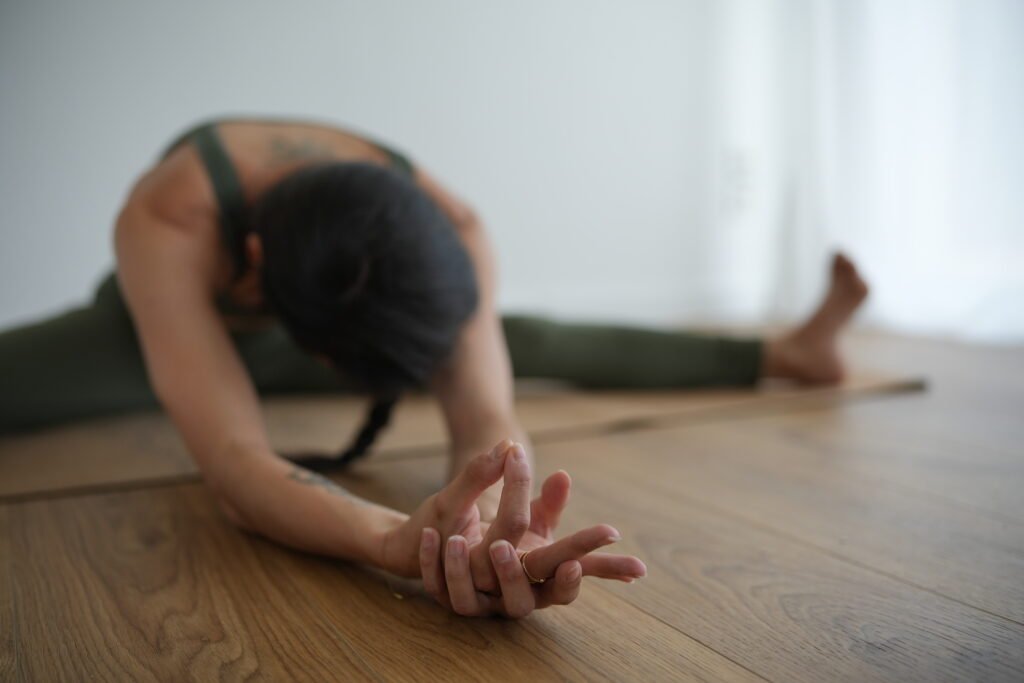 Yogi assis au sol en flexion avant jambe écartée, avec mudra